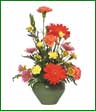 A vivid arrangement of red gerberas, yellow and orange carnations and lavender pompons.