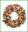 Mixed wreath in shades of pink, peach, lavender and purple using lilies, carntions, roses and pompons. Appropriate for funeral home.
