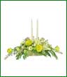 White lilies, yellow roses, white daisies, monte casino and solidago surround two candles.