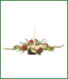 White candle is surrounded by red roses, pink gladiolus, white daisies, pink miniature carnations and monte casino.