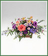 A table centerpiece of colorful mixed flowers including alstroemeria, delphinium, asters and standard carnations.