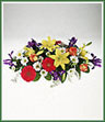 A table centerpiece featuring Konfetti roses, asiatic lilies, iris, gerbera and daisy spray mums