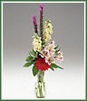 A  bud vase of blossoms including liatris, stock, gerbera, and alstroemeria.