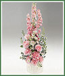 A ceramic baby  arrangement of pink larkspur, roses and carnations for a girl. Block container shown, but shape may vary.