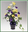 A classic urn vase filled with yellow alstromeria,  daisy spray mums and cornflower. Color of vase may vary.