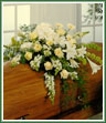 A casket spray  in all white to include such flowers as white lilies, roses, gerbera and snapdragons.