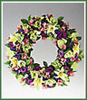 A solid flower wreath of mixed flowers such as gladioli florets, purple lisianthus, pink alstroemeria and cornflowers. Appropriate for funeral home.