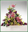 A fireside basket of mixed spring colors including pink lilies, violet stock, yellow daisy spray mums and solidaster.