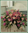 A low cascading design of lavender stock, pink lilies and roses to be placed on casket.