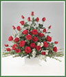 A white handled basket filled with red roses, white stock and huckleberry