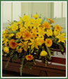 A casket spray of yellow lilies, gerbera, roses and eucalyptus.