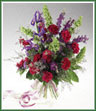 A hand tied bouquet of blue iris, fuchsia carnations, purple larkspur, statice and Misty Blue limonium with moluccella accents.