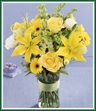 Beautiful as an early summer sunrise, this bouquet of yellow lilies, roses and mini Gerbera daisies mingle with white larkspur and lisianthus in a simple clear glass vase. A thoughtful gift for any occasion. Style of vase may vary.