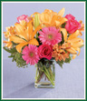 What a perfect summer day bouquet! Glorious orange lilies with hot pink roses and Gerbera daisies are arranged in a clear glass rectangular vase with a sprinkling of Queen Anne's lace and seeded eucalyptus. A splendid birthday or anniversary greeting, or a cheery get well wish! Style of vase may vary.