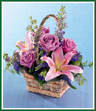 A birch bark basket with a handle holds lavender roses and pink Oriental lilies along with light purple larkspur and gray-green eucalyptus for a softly muted arrangement. Deep purple veronica is added for a surprisingly delicate touch. It's a delightful basket to bring along to any summer party. Style of basket may vary.