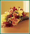 Grace your fall table with this cornucopia brimming with orange roses, red spray roses, and peach lilies. We've added dried gourds, hypericum and oak leaves to make a sumptuous horn of plenty.
