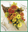 Our traditional cornucopia is abundant with the rich colors of the season. Warm orange Gerbera daisies, yellow alstroemeria and bronze pompons flow from this horn-of-plenty and are accented with hypericum, solidago, and yarrow. The perfect decoration for your fall table.