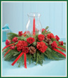 Beautify your table or buffet with this traditional red and green centerpiece. Red spray roses and red carnations are enhanced by pine cones, red bows and an assortment of Christmas greens. A taper candle inside a glass hurricane offers a warm holiday glow.
