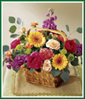 This brightly colored bouquet arrives in a basket and will fill any room with color. Arrangement includes peach spray roses, hot pink ranunculus, orange mini gerbera daisies, purple stock and more.